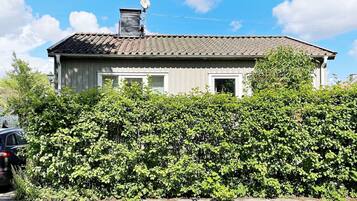 A house with a tiled roof, a satellite dish, and a hedge in front.