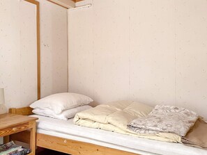 En säng för en person med en träram, ett sängbord med en lampa och en vägg med ett mönster.
