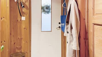 A wooden door with a frosted glass window, a towel hanging on a hook, a blue bag, and a wooden stool.