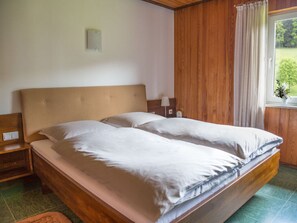 Relax in this serene bedroom with a large bed, nightstand, and window with curtains.