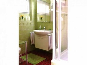 Bathroom features a single sink, mirror, and window, with a green rug and towels.