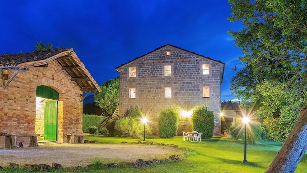 A stone building with a green door, a well-maintained lawn, and outdoor lighting.