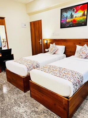 A hotel room with two wooden beds, a wooden wardrobe, a painting on the wall, and a carpeted floor.