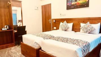 A double bed with a floral bedspread, two nightstands, a wooden wardrobe, and a painting on the wall.