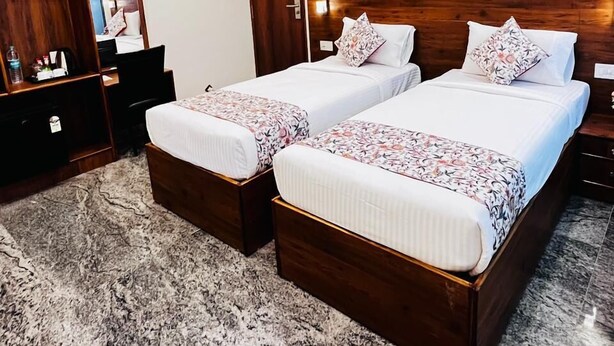Habitación de hotel con dos camas individuales, un ventilador de techo, un cuadro en la pared y un armario de madera.