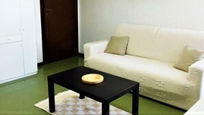 En stue med en hvid sofa, et sort sofabord og en tæppe med et mønster.