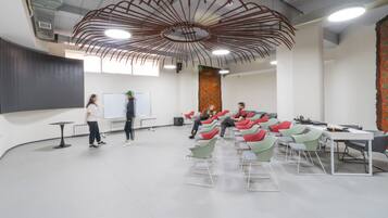 A modern conference room with a unique ceiling design, a whiteboard, and a large tapestry.
