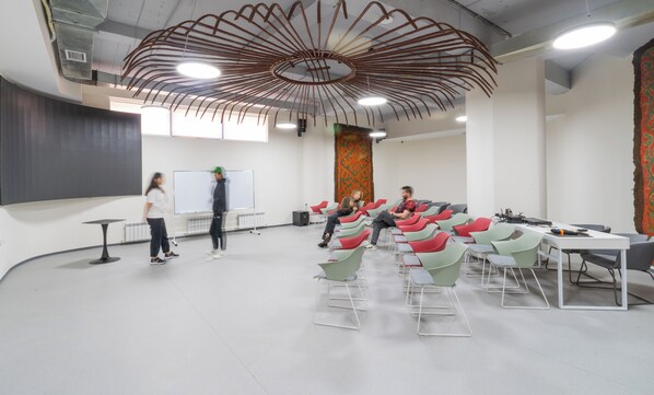 A modern conference room with a unique ceiling design, a whiteboard, and a large tapestry. - ololoYurt ethno-hostel & coworking (Bishkek)