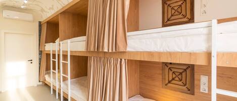 A bunk bed room with a wooden headboard, a ladder, and a wall-mounted light fixture.
