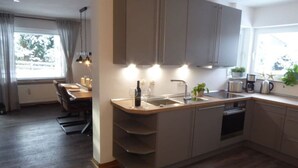 A modern kitchen with a central island, built-in appliances, and a dining area with a table and chairs. - Nice Apartment in Hahnenklee (Goslar)