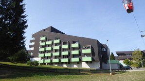 A modern multi-story building with balconies, a cable car system, and a green landscape. - Nice Apartment in Hahnenklee (Goslar)