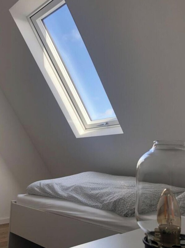 A bedroom with a skylight, a bed, and a lamp. - Torbogenhuus No. 5 Comfortable Holiday Residence (Norderney)