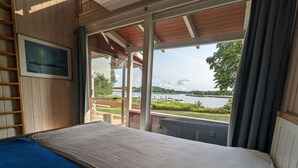 A room with a bed, a window, and a view of a lake and trees. - Schleipanorama Modern Retreat (Brodersby)