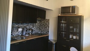 Keittiössä on tummat kaapit, mikroaaltouuni ja laatoitettu seinä välitilassa.
