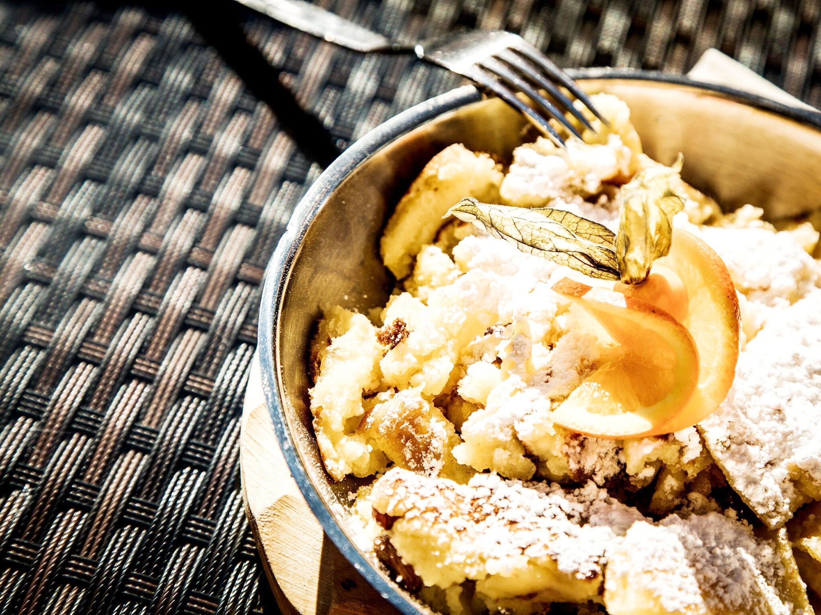 Eine Schüssel mit Essen und einem Löffel auf einer gewebten Unterlage.