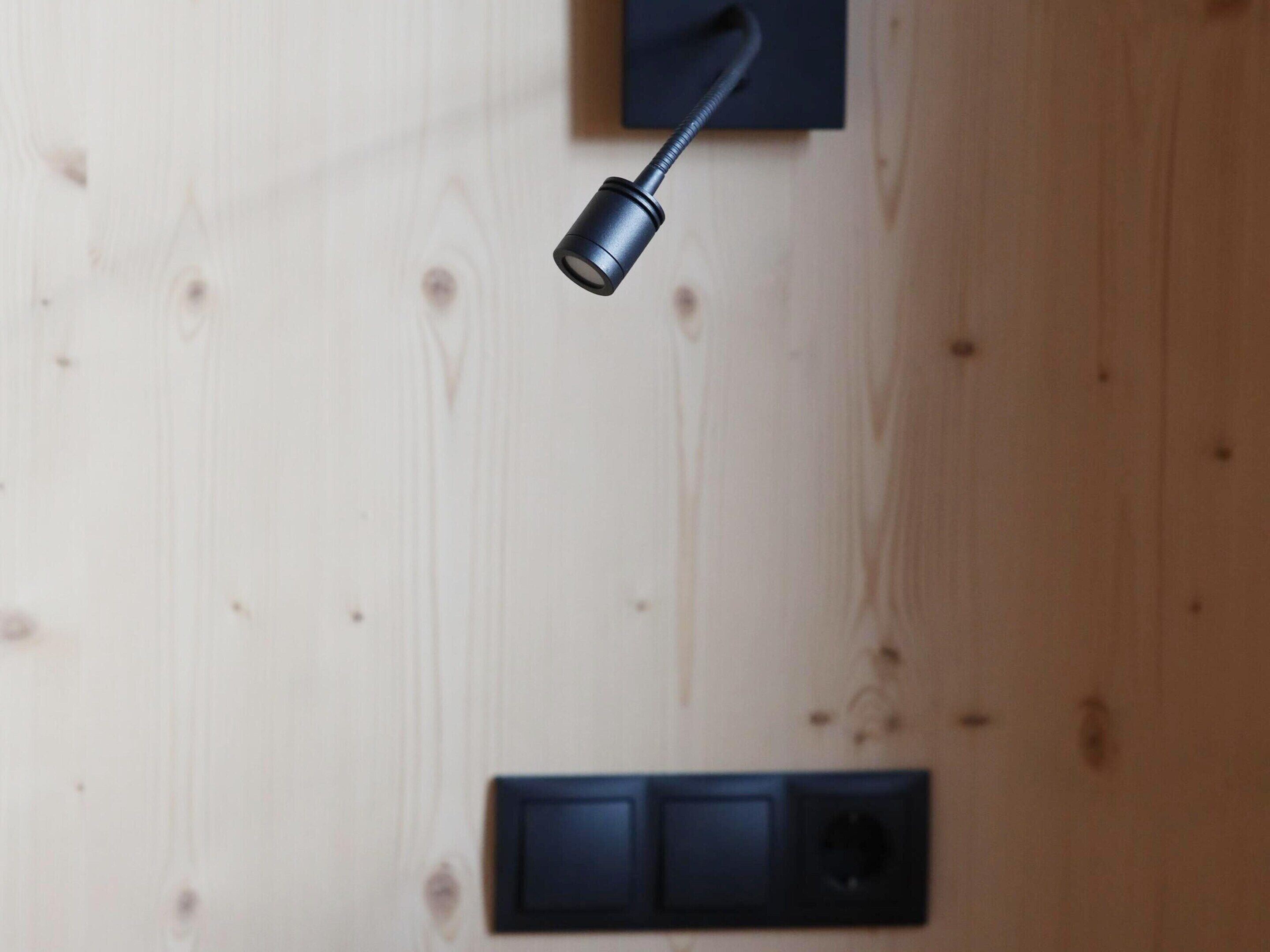 A modern room with a wooden wall, a black switchboard, and a black cylindrical object.