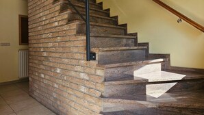 Un escalier avec un mur en briques d’un côté et une main courante en bois.