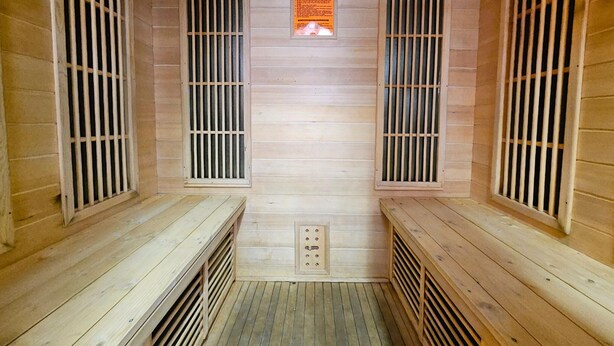Un sauna aux murs et aux bancs en bois, doté de fenêtres grillagées et d’un système de ventilation.
