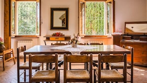A dining room with a wooden table and chairs, large windows with metal bars, a mirror, and a radiator. - Belvilla by OYO Villa Sapori (Pergola)