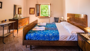 A bedroom with a wooden bed, a desk, a chair, and a window with a view of greenery. - Belvilla by OYO Villa Sapori (Pergola)