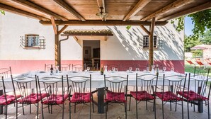 An outdoor dining area with tables and chairs under a wooden pergola, connected to a building with a red and white facade. - Belvilla by OYO Villa Sapori (Pergola)