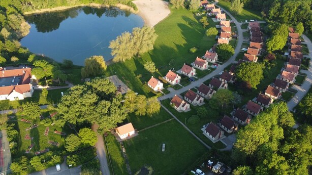 Vista aérea de una zona residencial con casas, un estanque y zonas verdes.