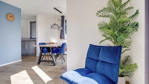 Un espacio de estar moderno con una silla azul, comedor y planta en maceta.