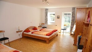 Une chambre à coucher avec un lit en bois, deux chaises, une armoire en bois et une fenêtre avec des rideaux.