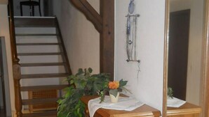 A wooden staircase with a chair at the top, a wooden cabinet with a plant, and a mirror on the wall. - Ferienhof Schwienhorst - Ferienwohnung Bauernstübchen. 1-7 Pers (Warendorf-Hoetmar)