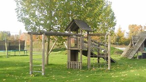 A playground with a wooden climbing structure and a slide. - Ferienhof Schwienhorst - Ferienwohnung Bauernstübchen. 1-7 Pers (Warendorf-Hoetmar)