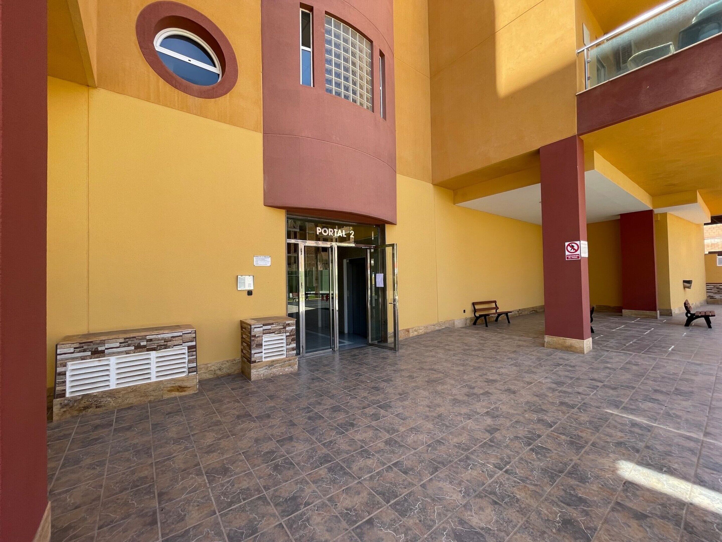 A building entrance with a glass door labeled "PORTAL 2" and a bench outside.