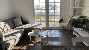 Een moderne woonkamer met een bank, een klein rond tafeltje, een stoel en een televisie.