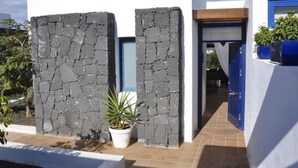 A modern building with stone walls, a blue door, and a tiled entrance. - Villa Bella Vista Blu (Yaiza)