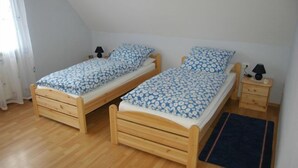A small room with two wooden beds, each with a matching nightstand and lamp. - Ferienwohnung Rottmann, 1-4 Pers (Warendorf-Einen)
