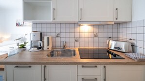 Een moderne keuken met witte kasten, een roestvrijstalen spoelbak, een koffiezetapparaat, een broodrooster en een betegelde spatwand.