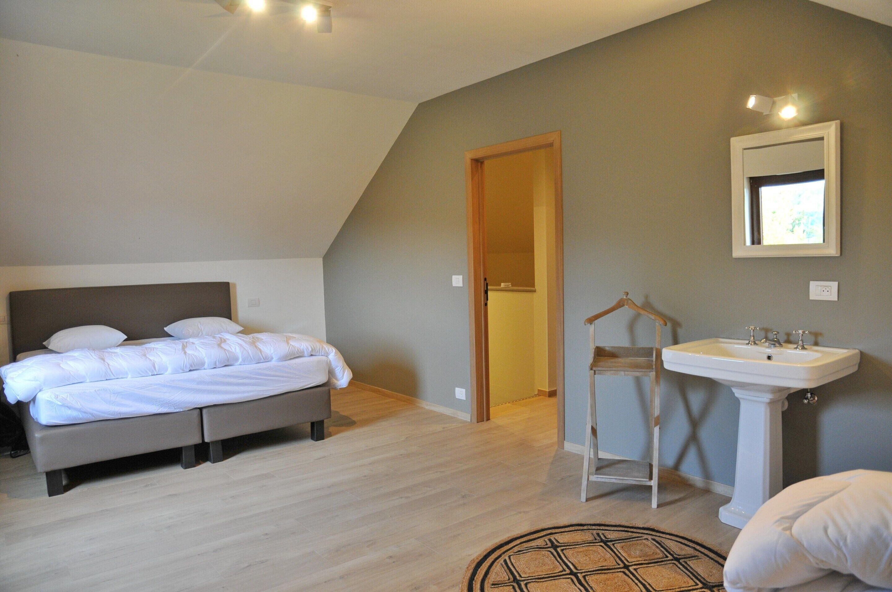 A bedroom with a bed, a bedside table, a hanging light, and a wall-mounted mirror.