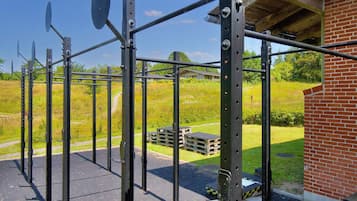 Eine Metall-Trainingsstruktur mit Dach, umgeben von einem Backsteinhaus und einem grünen Rasenfeld.