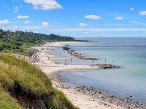 A coastal beach with rocky shores, clear skies, and a distant shoreline. - 6 Person Holiday Park Home in Gilleleje (Gilleleje)