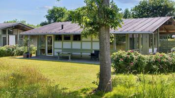 A two-story building with a covered porch and a small garden area.