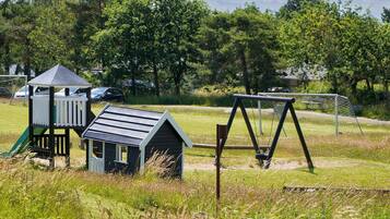 A playground with a slide, swing set, and small playhouse.