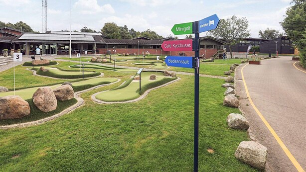 A miniature golf course with directional signs for 'Minigolf', 'Café Kyshuset', and 'Badeanstalt'. - 6 Person Holiday Park Home in Gilleleje (Gilleleje)
