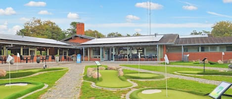 A golf course with a clubhouse, a paved walkway, and a well-maintained lawn.