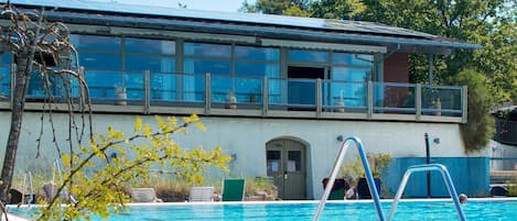 A swimming pool with a metal ladder, a yoga room, and a building with large windows and a door labeled "YOGA".