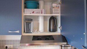 A kitchen with a built-in microwave, a kettle, a coffee maker, and a box of tea. - Holiday Apartment Heitmann (Hilders)
