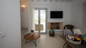 Een moderne woonkamer met een open haard, een flatscreen televisie en een eethoek met een tafel en stoelen.
