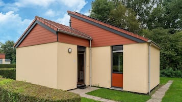 A single-story building with a red-tiled roof, beige exterior walls, and a small front door.