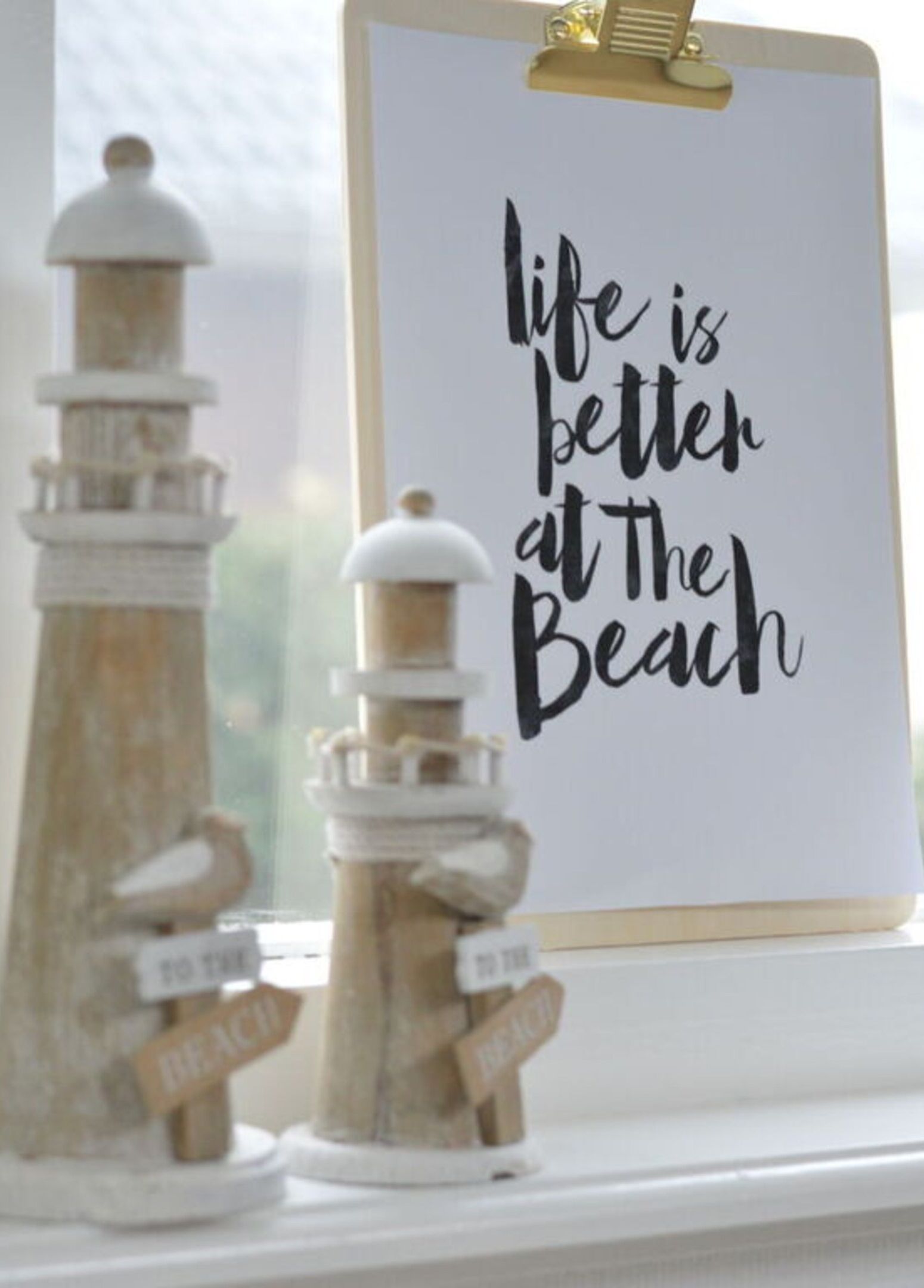 Une citation inspirante encadrée, qui dit : « La vie est plus belle à la plage », est posée sur le rebord d’une fenêtre.