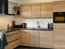 A modern kitchen with wooden cabinets, a stainless steel sink, and a built-in oven.