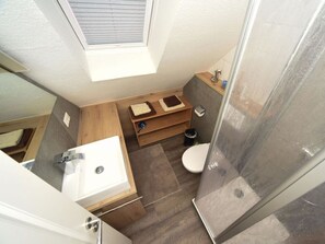 Ein kleines Badezimmer mit Dusche, Waschbecken und Toilette.