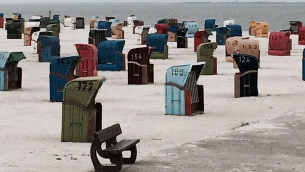 A row of numbered mailboxes in various colors, with a bench in the foreground. - Holiday Home Nispel Comfortable Vacation Home (Dornum)